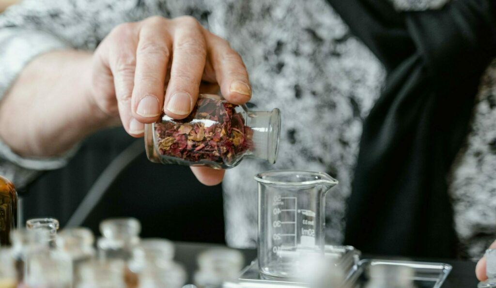 Person Holding Clear Glass Bottle with Dried Leaves